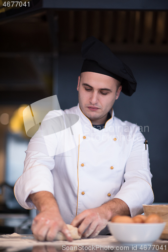 Image of young chef preparing dough for pizza