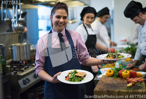 Image of young waitress showing dishes of tasty meals