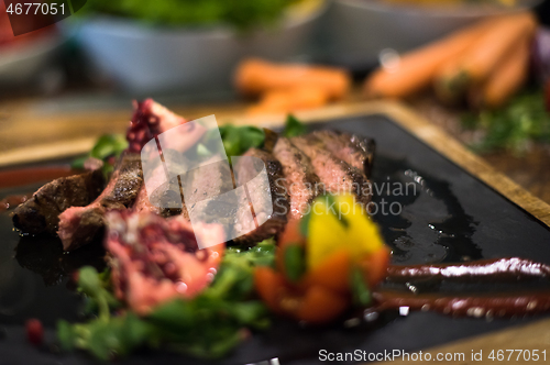 Image of Juicy slices of grilled steak on wooden board