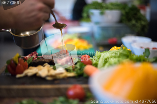 Image of Chef hand finishing steak meat plate