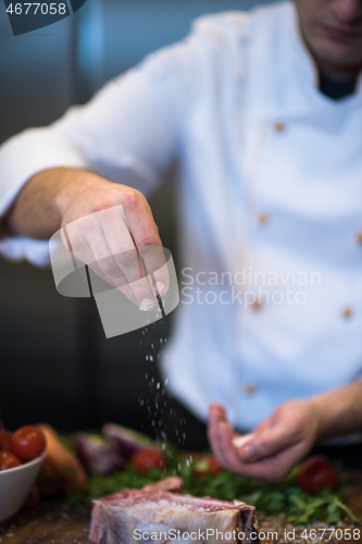 Image of Chef putting salt on juicy slice of raw steak