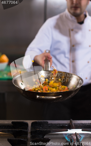 Image of chef flipping vegetables in wok