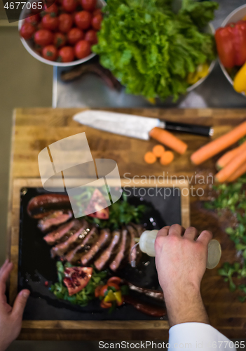 Image of top view of Chef finishing steak meat plate