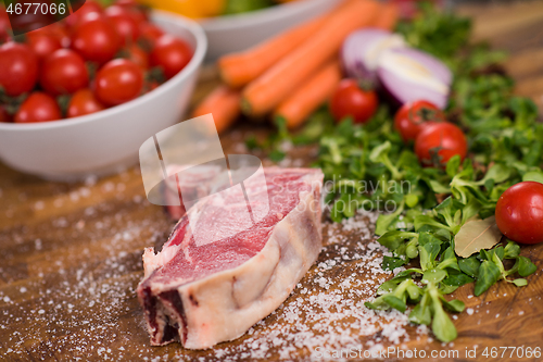 Image of Juicy slice of raw steak on wooden table