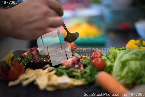 Image of Chef hand finishing steak meat plate