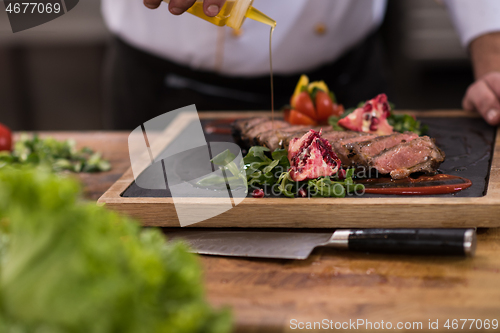 Image of Chef finishing steak meat plate