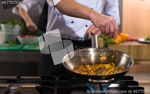 Image of chef putting spices on vegetables in wok