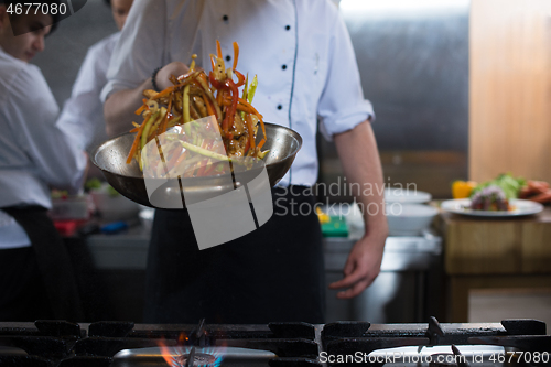 Image of chef flipping vegetables in wok