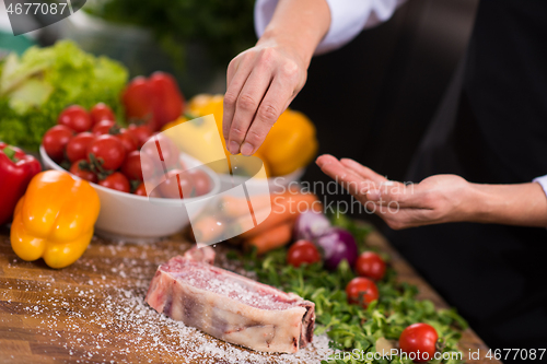 Image of Chef putting salt on juicy slice of raw steak