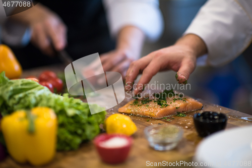 Image of Chef hands preparing marinated Salmon fish