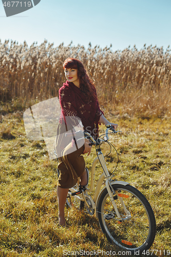 Image of Pretty girl riding bicycle in field