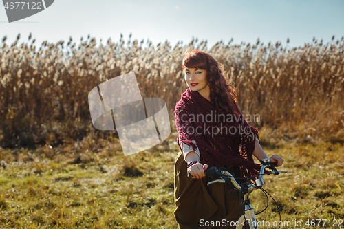 Image of Pretty girl riding bicycle in field