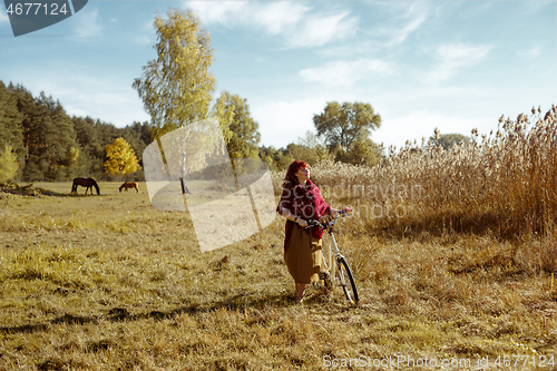 Image of Pretty girl riding bicycle in field