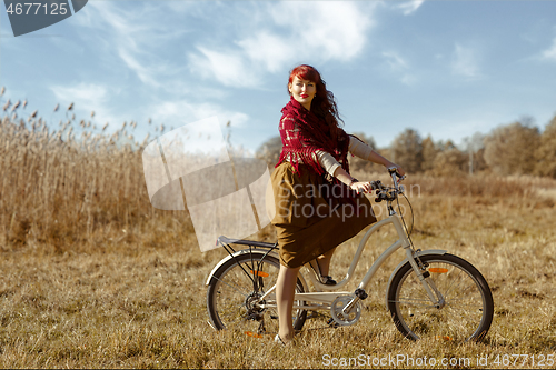 Image of Pretty girl riding bicycle in field