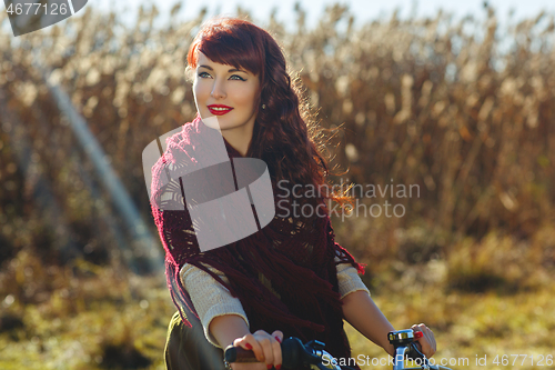 Image of Pretty girl riding bicycle in field