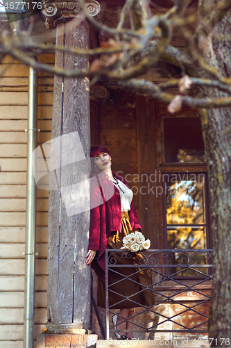 Image of Girl standing on old house balcony