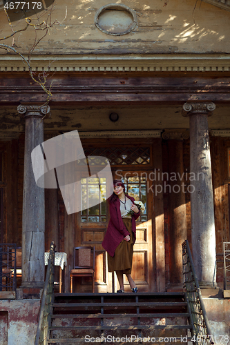 Image of Girl standing on old house balcony