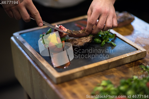 Image of closeup of Chef hands serving beef steak