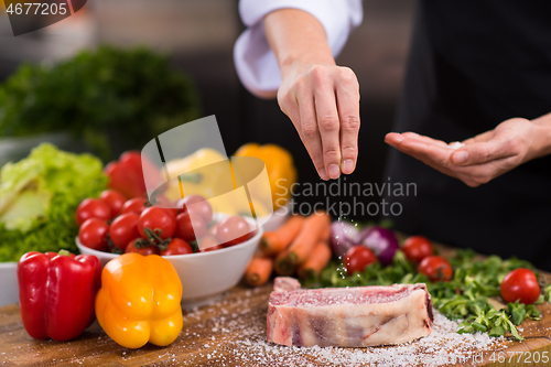 Image of Chef putting salt on juicy slice of raw steak