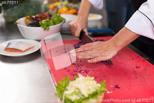 Image of chef hands cutting salad for burger