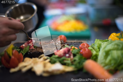 Image of Chef hand finishing steak meat plate