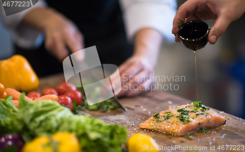 Image of Chef hands preparing marinated Salmon fish