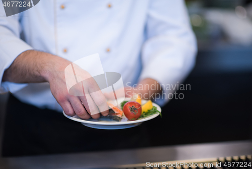 Image of chef hands cooking grilled salmon fish