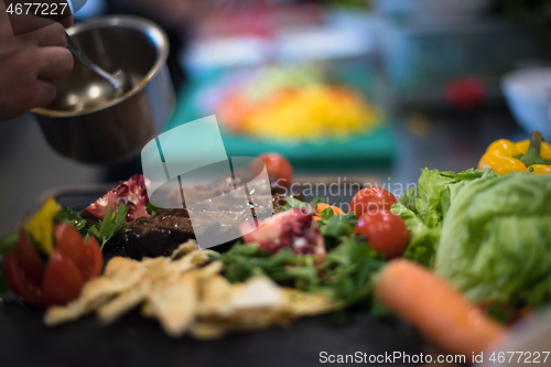 Image of Chef hand finishing steak meat plate