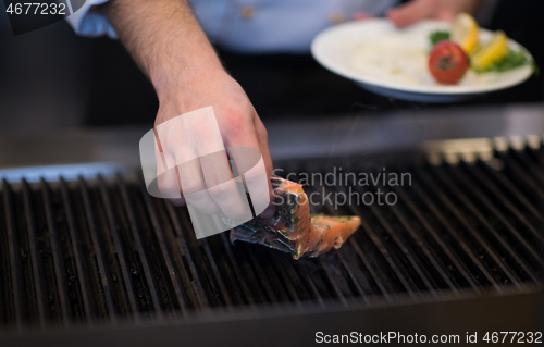 Image of chef hands cooking grilled salmon fish