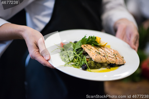 Image of Chef hands holding dish of fried Salmon fish fillet