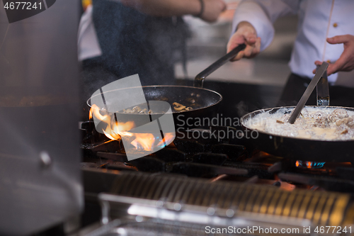 Image of chef preparing food, frying in wok pan