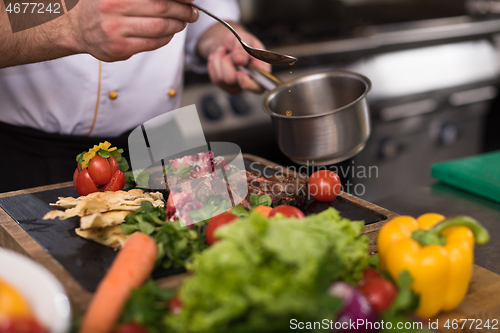 Image of Chef hand finishing steak meat plate