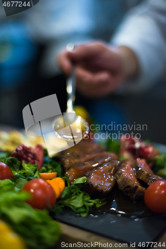 Image of Chef hand finishing steak meat plate