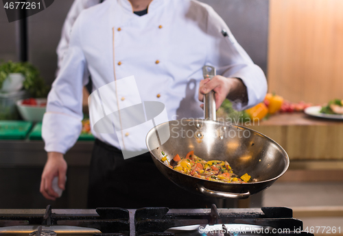 Image of chef flipping vegetables in wok