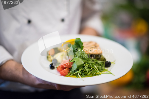 Image of Chef hands holding dish of fried Salmon fish fillet