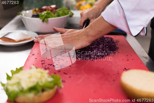 Image of chef hands cutting salad for burger