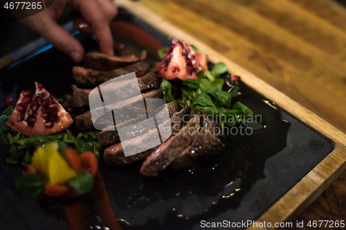 Image of closeup of Chef hands serving beef steak