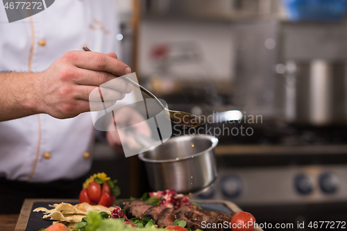 Image of Chef hand finishing steak meat plate