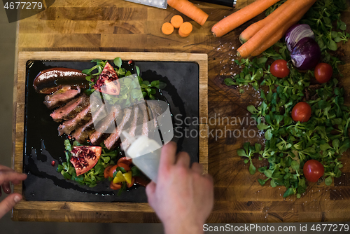 Image of top view of Chef finishing steak meat plate