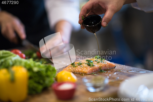 Image of Chef hands preparing marinated Salmon fish