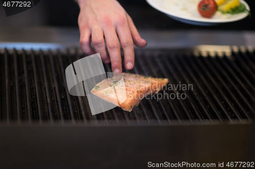 Image of chef hands cooking grilled salmon fish