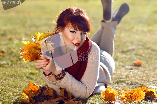 Image of Girl lying on ground with yellow leaves