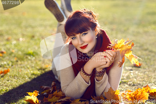 Image of Girl lying on ground with yellow leaves