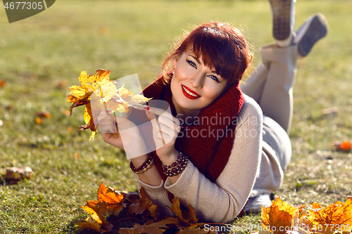 Image of Girl lying on ground with yellow leaves