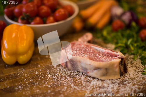 Image of Juicy slice of raw steak on wooden table