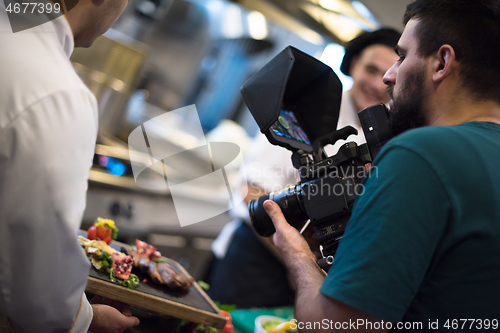 Image of videographer recording while team cooks and chefs preparing meal