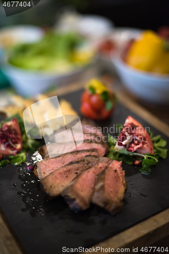 Image of Juicy slices of grilled steak on wooden board