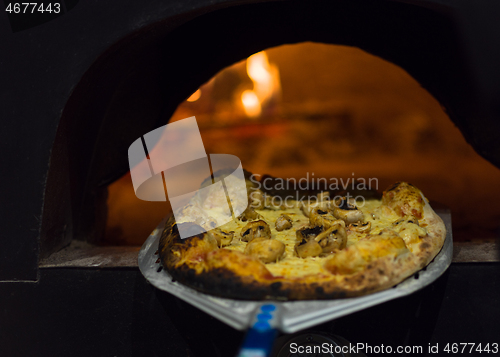 Image of chef removing hot pizza from stove