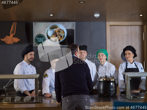 Image of chefs in the kitchen presenting dish of tasty meal