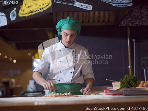 Image of chef putting fresh mushrooms on pizza dough